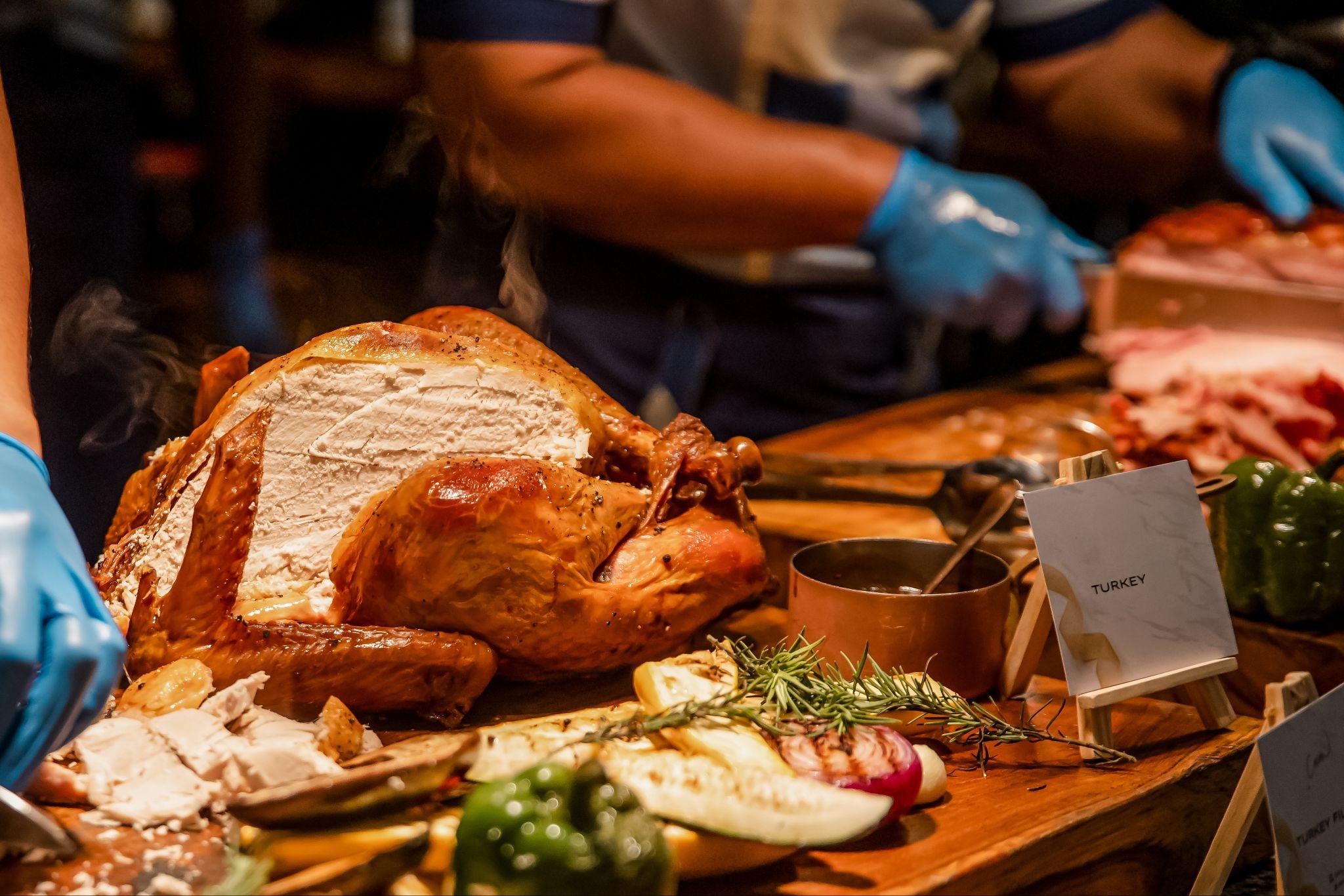 Chef carving roasted holiday turkey with seasonal vegetables