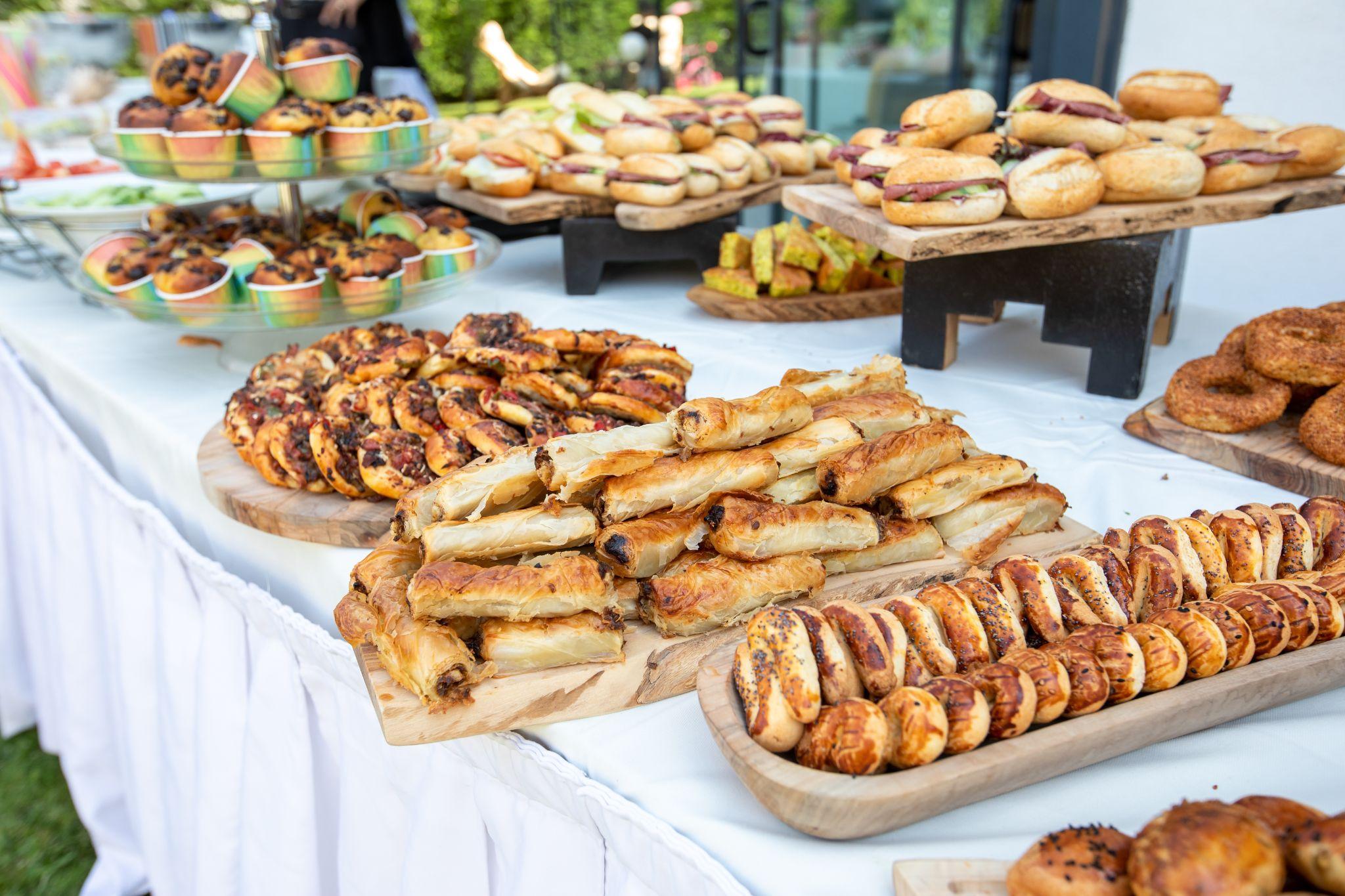 Table with pastries, muffins, and mini sandwiches at an outdoor wedding