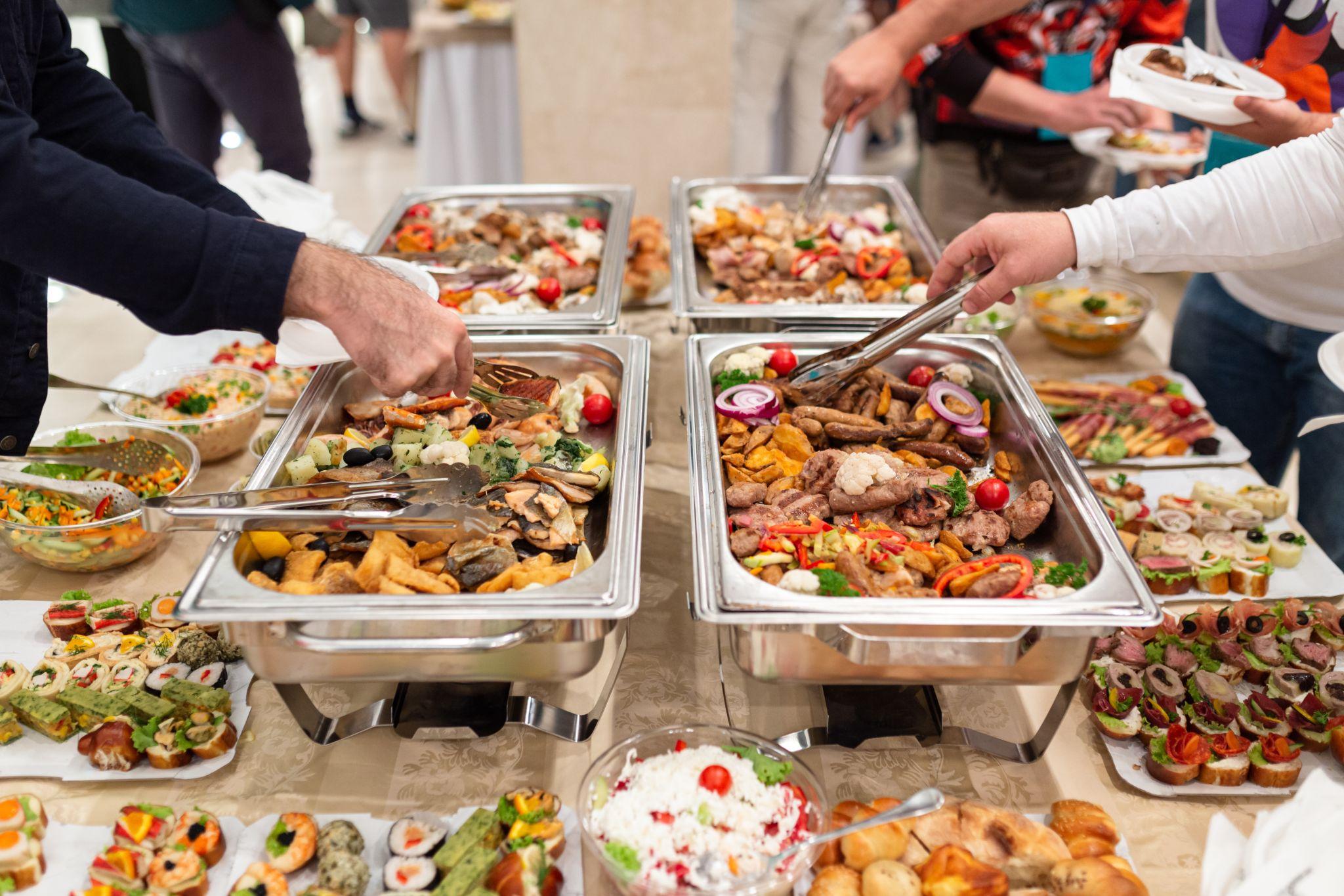 Guests serving themselves from a wedding buffet station.
