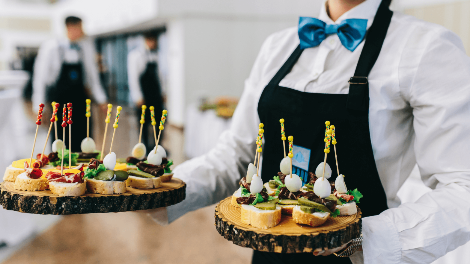 A waitress carrying two platters of food items