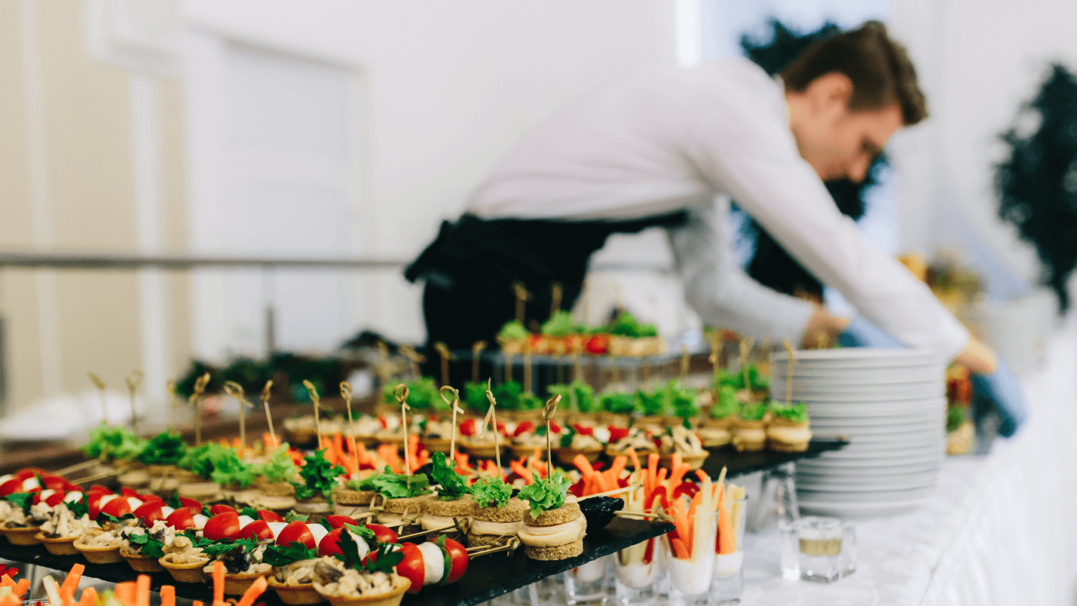 A platter of vegetables with a waiter adding more
