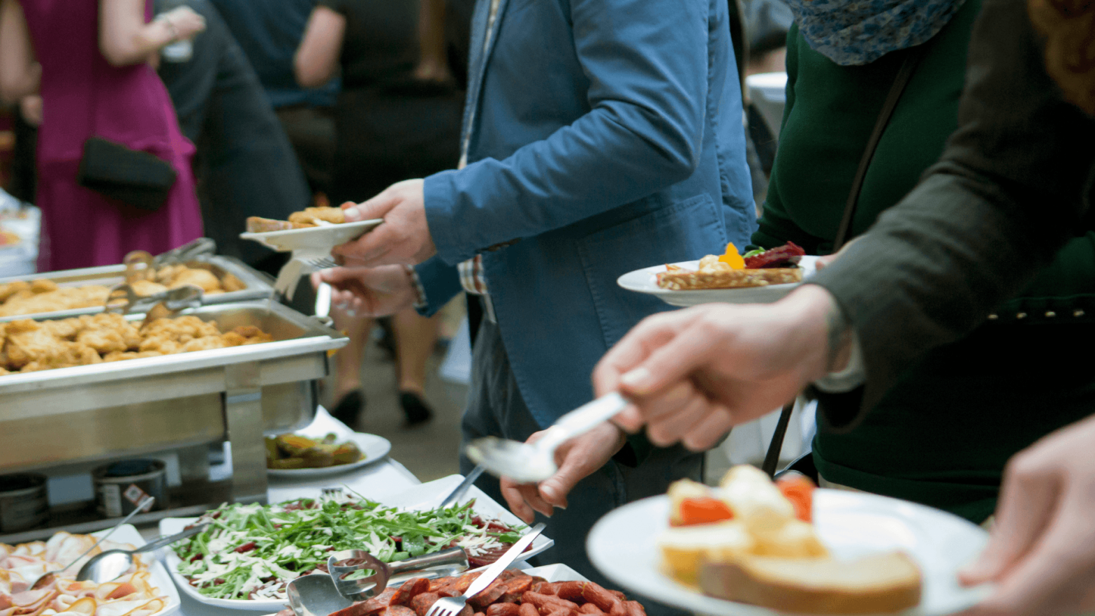 People at a catered event filling their plates with food