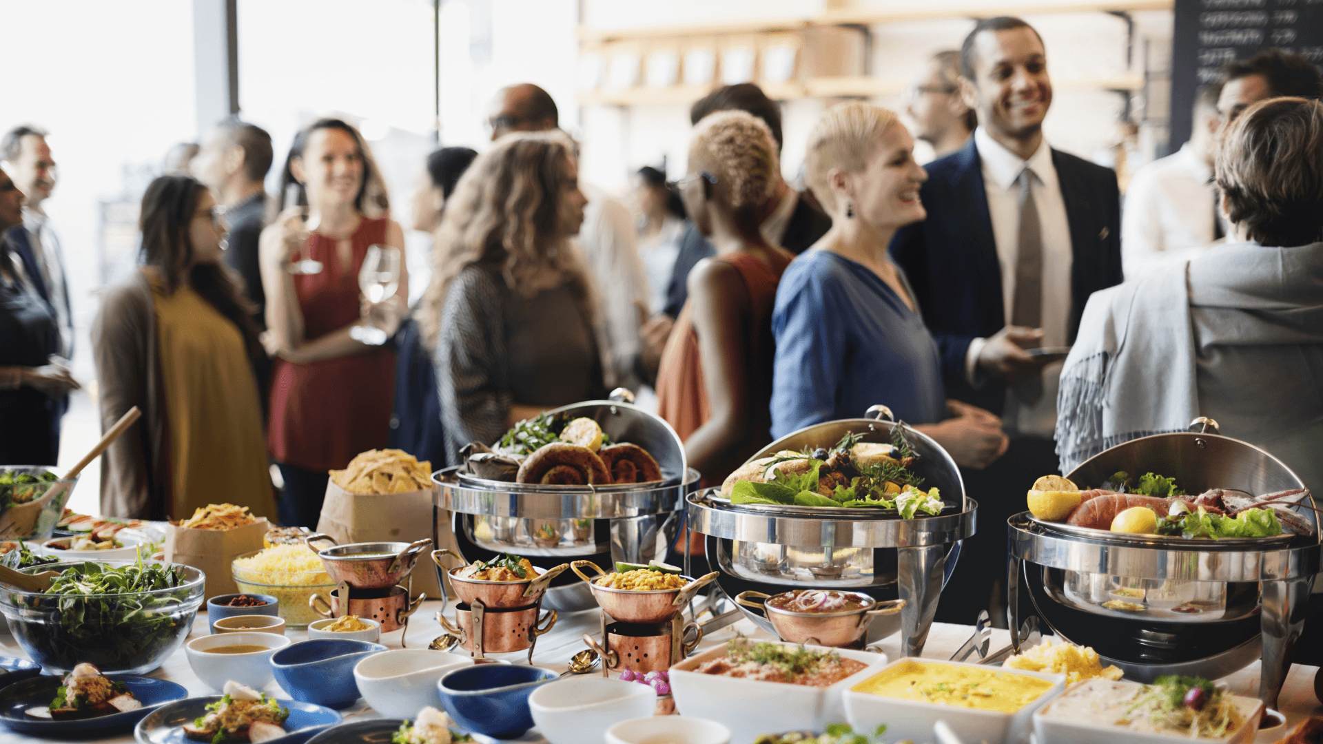 A platter of vegetables and meats while people at the event socialize