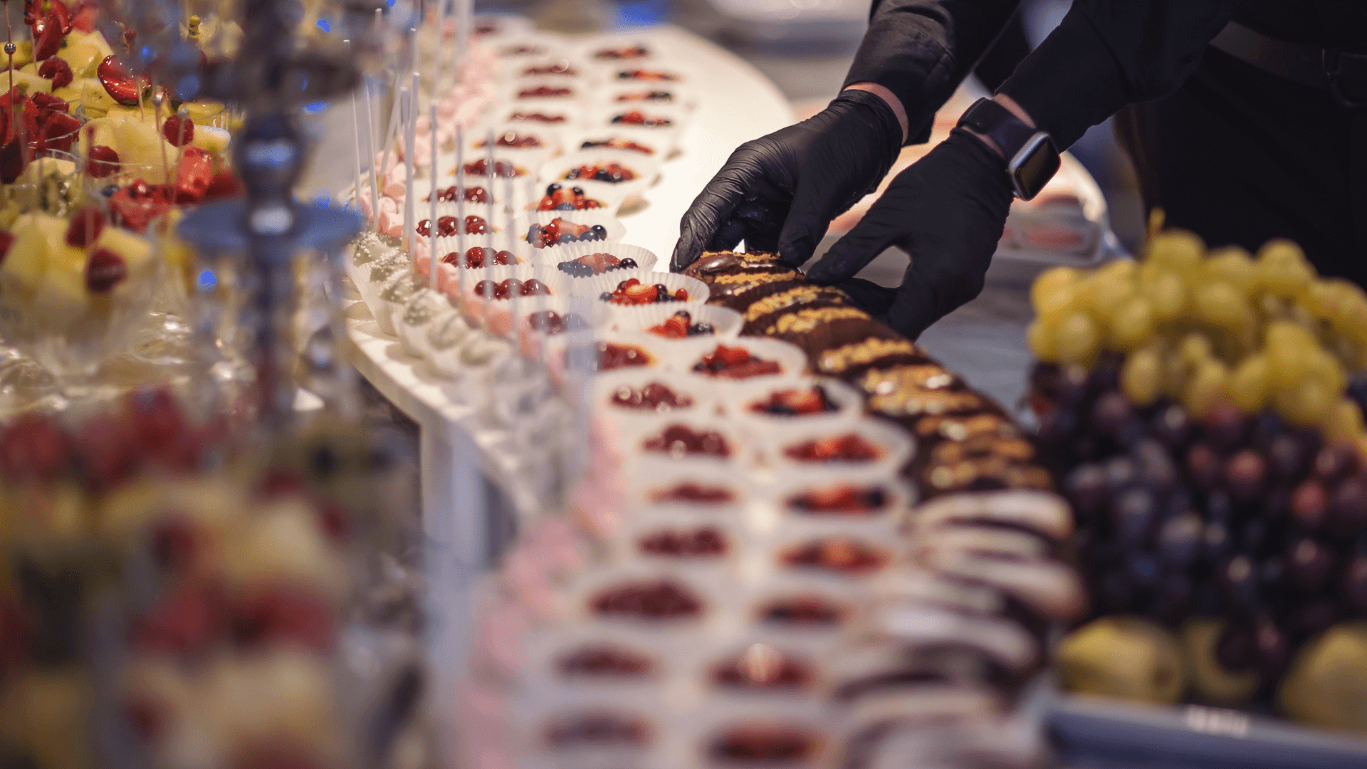 A waiter preparing a table full of desserts and fruits