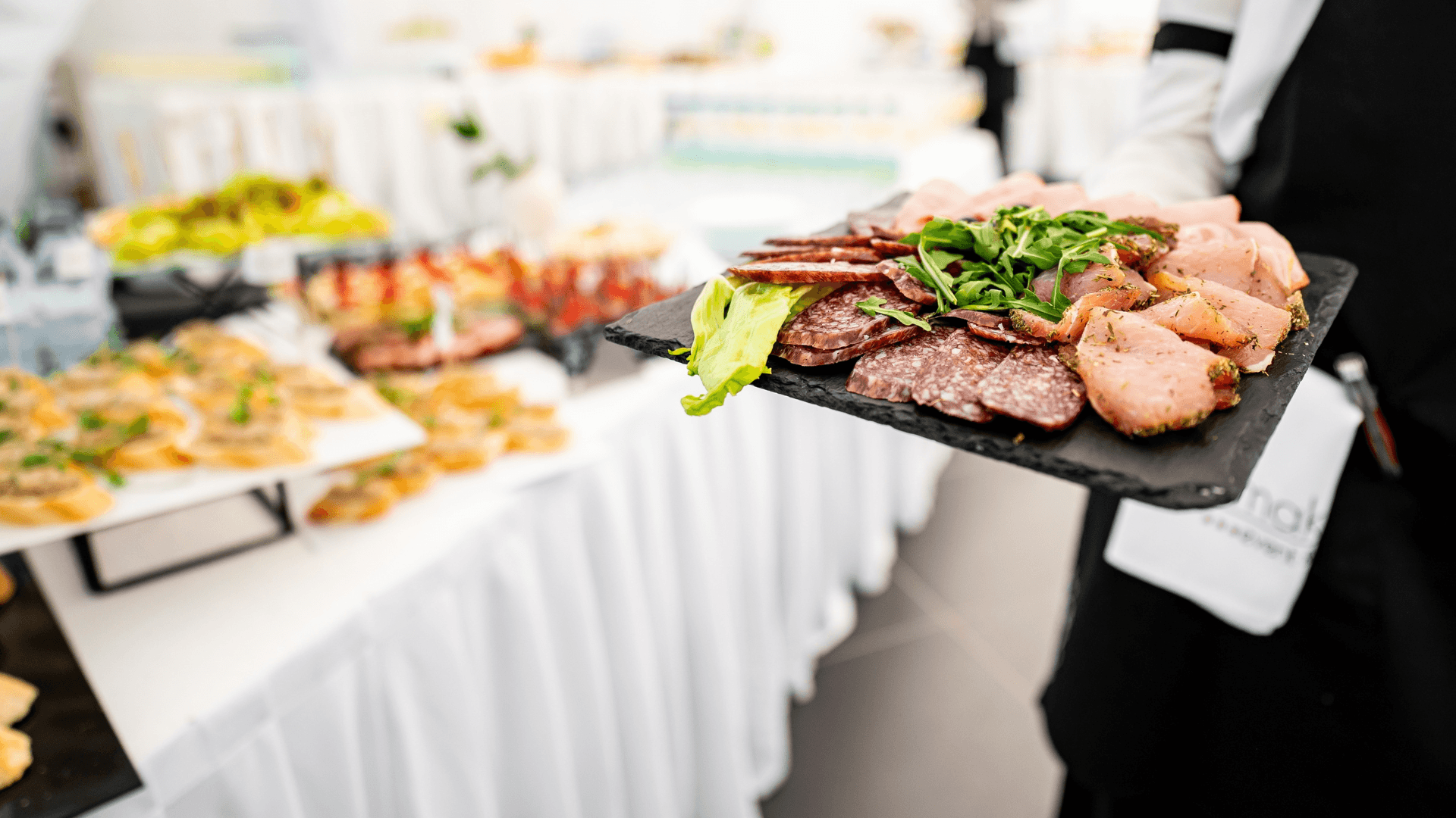 A platter of meats being presented by a waiter